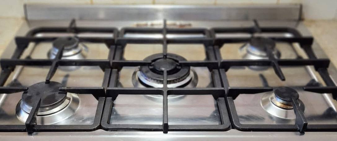 The same gas stovetop after cleaning, with clean enamel and degreased burner caps