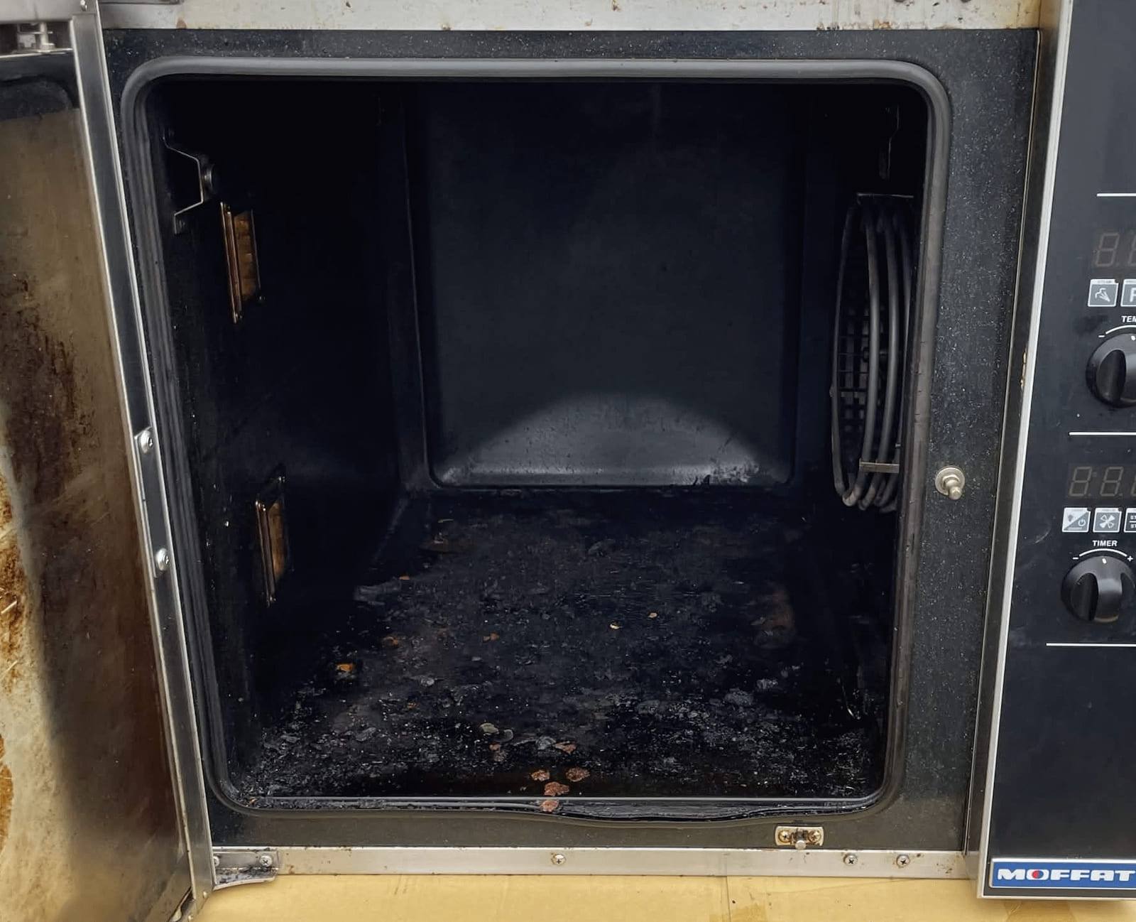 Large stainless oven with the cavity blackened by heavy carbon build-up
