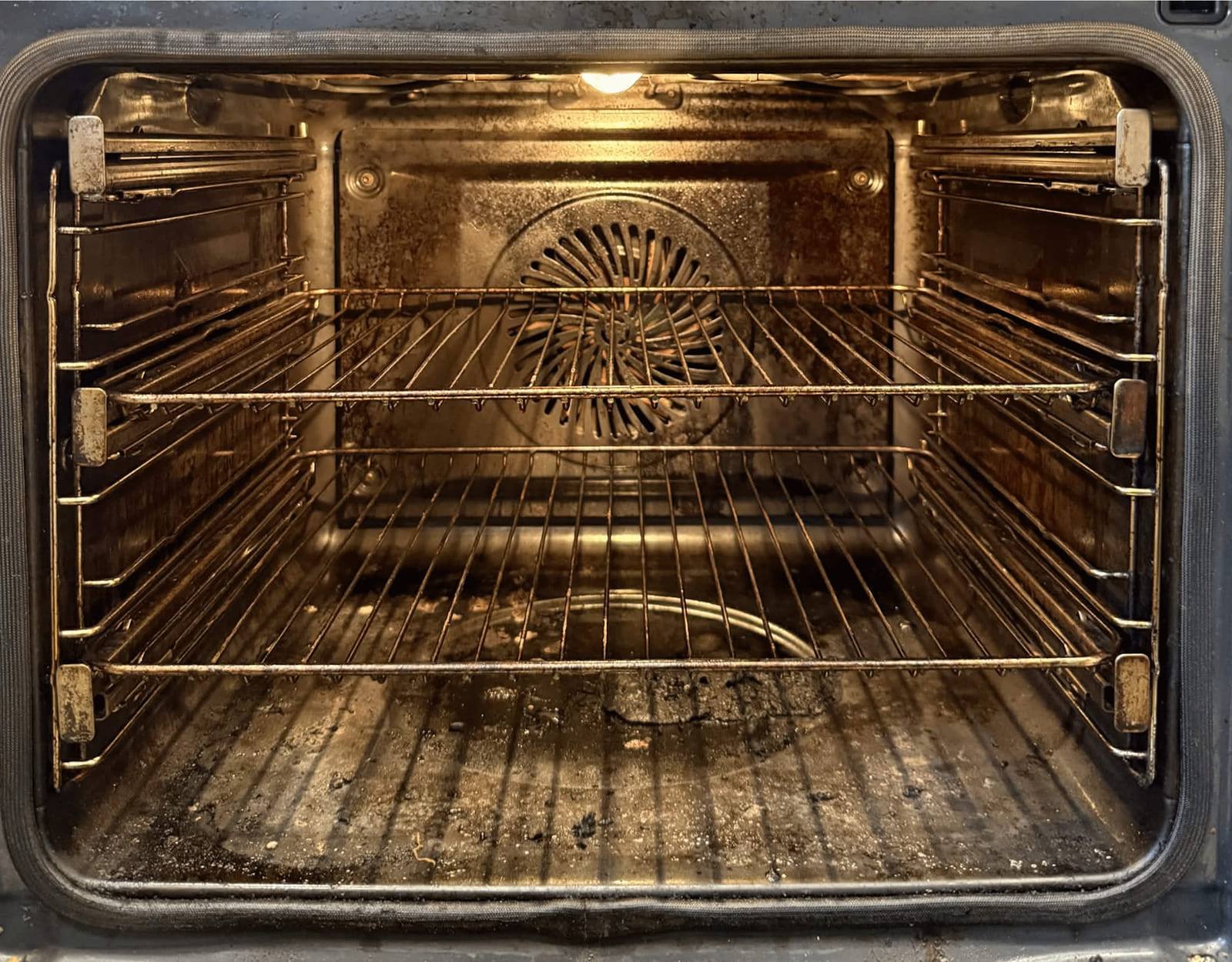 Oven cavity before cleaning, with the walls, racks and fan cover coated in brown baked-on grease