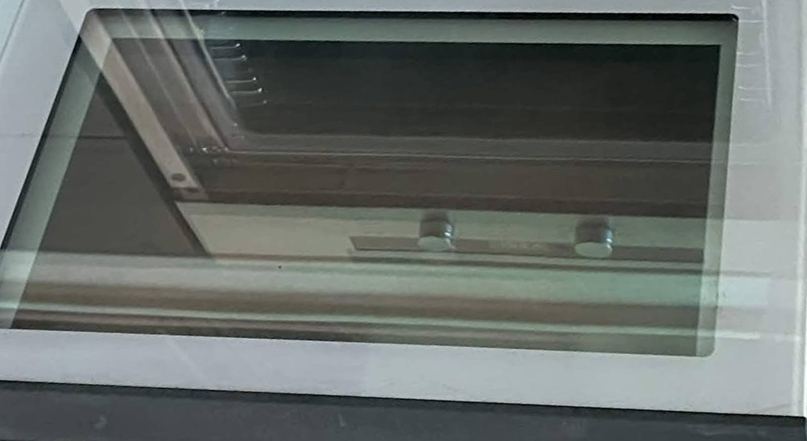 The same oven door glass after cleaning, fully transparent and ready to reassemble