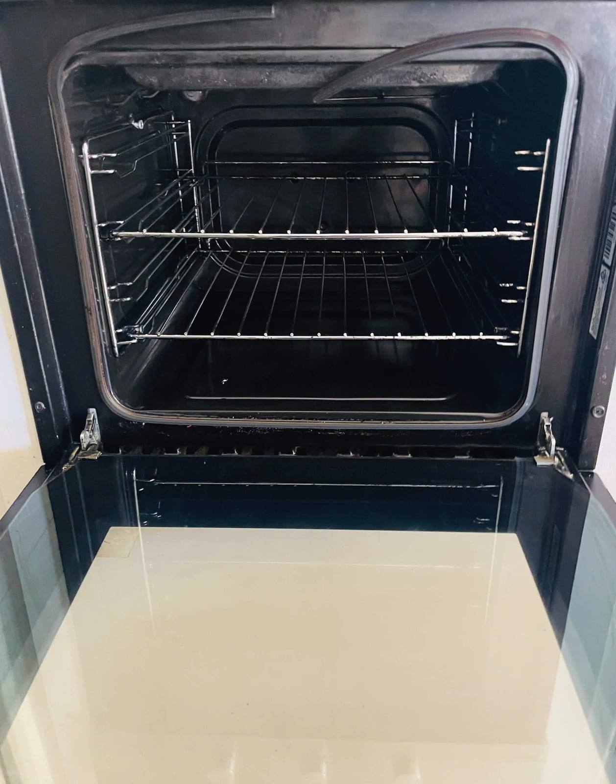 The same oven after cleaning, with clean runners and a door tray free of burnt residue