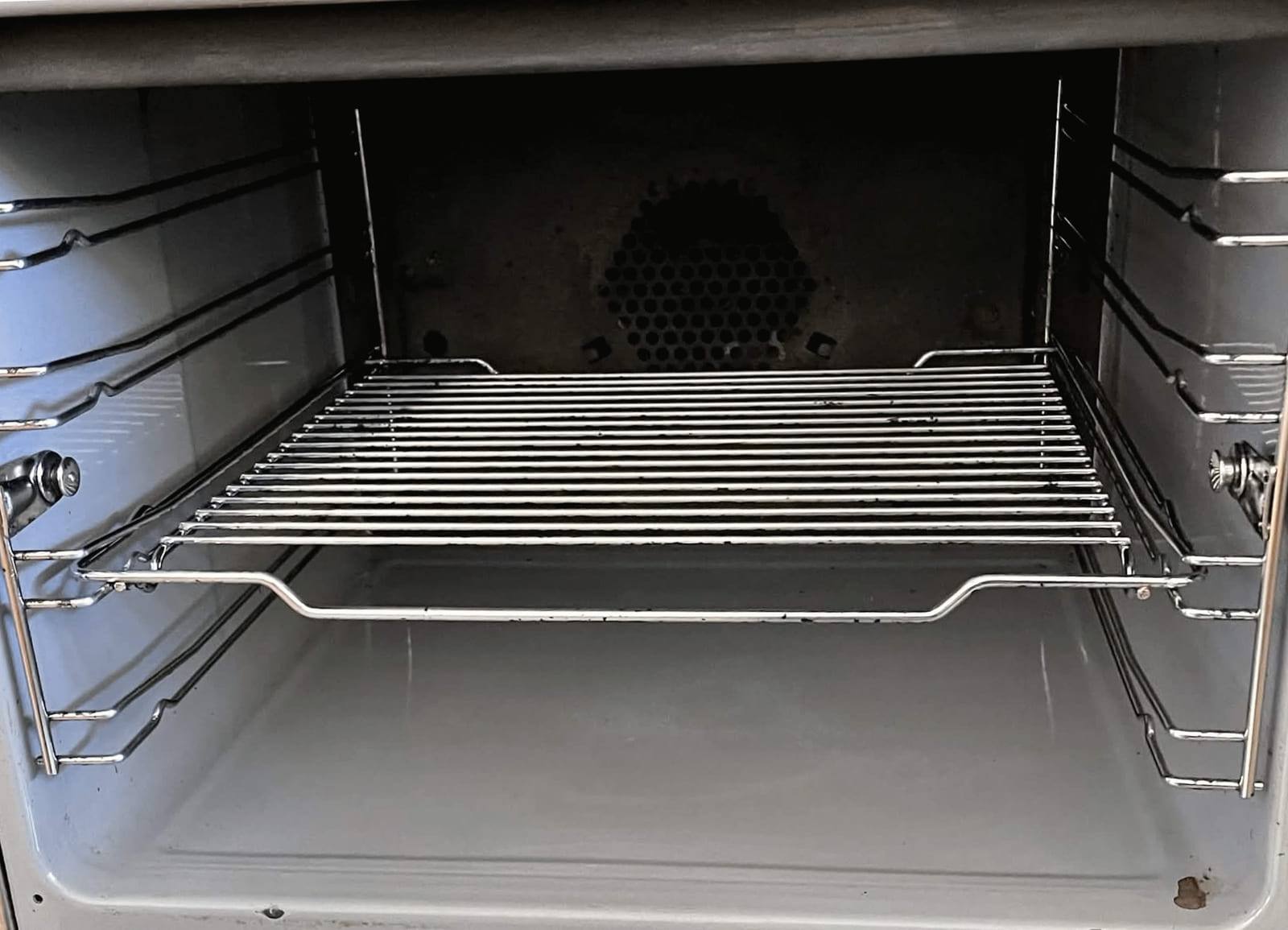 The same oven interior after cleaning, with bright racks and a clear door tray